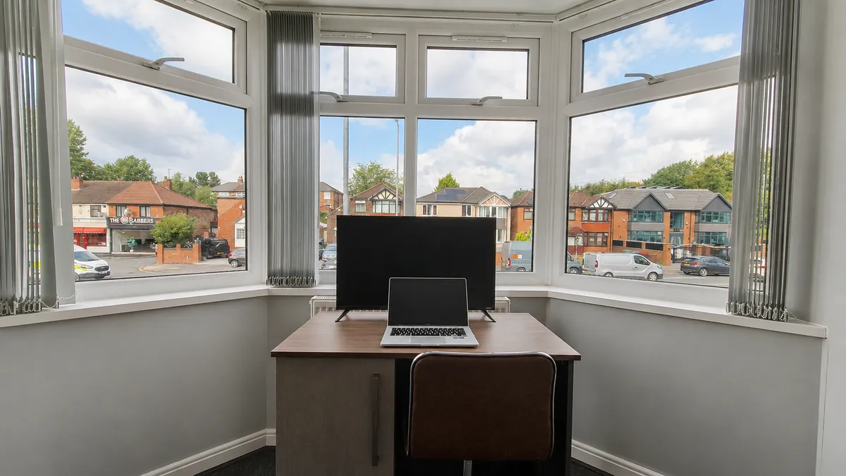 Desk and monitor set up in a bay window looking over the street