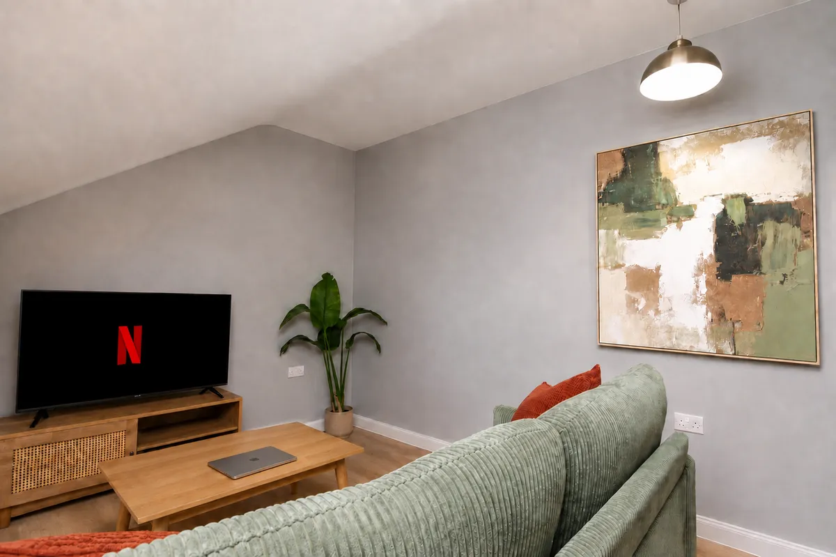 Living room with a corner sofa, smart TV and coffee table under a sloped ceiling